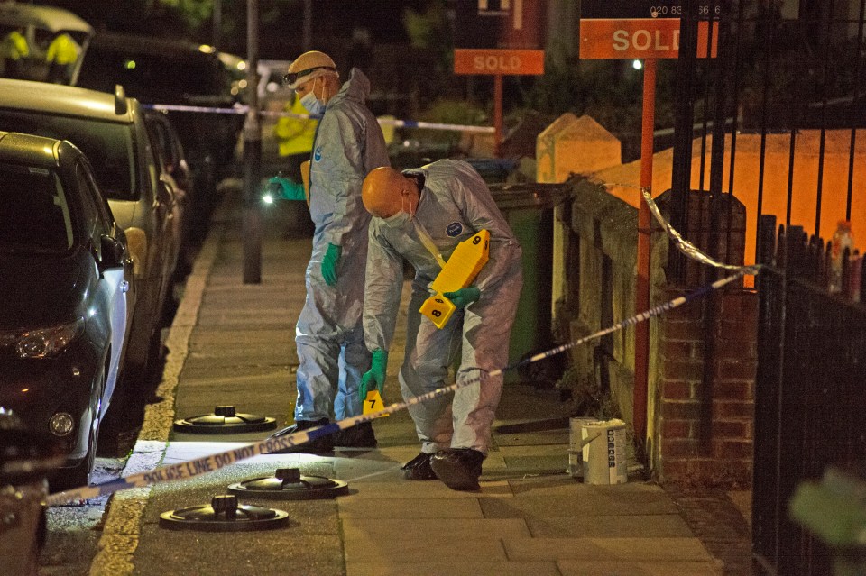 two forensic officers are looking for evidence in front of a sold sign