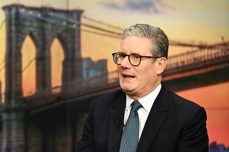 a man in a suit and tie stands in front of a bridge