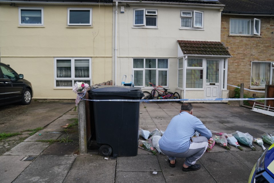 a man kneeling on the sidewalk in front of a house