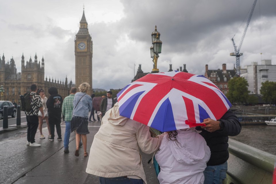 a person holding a red white and blue umbrella in front of big ben