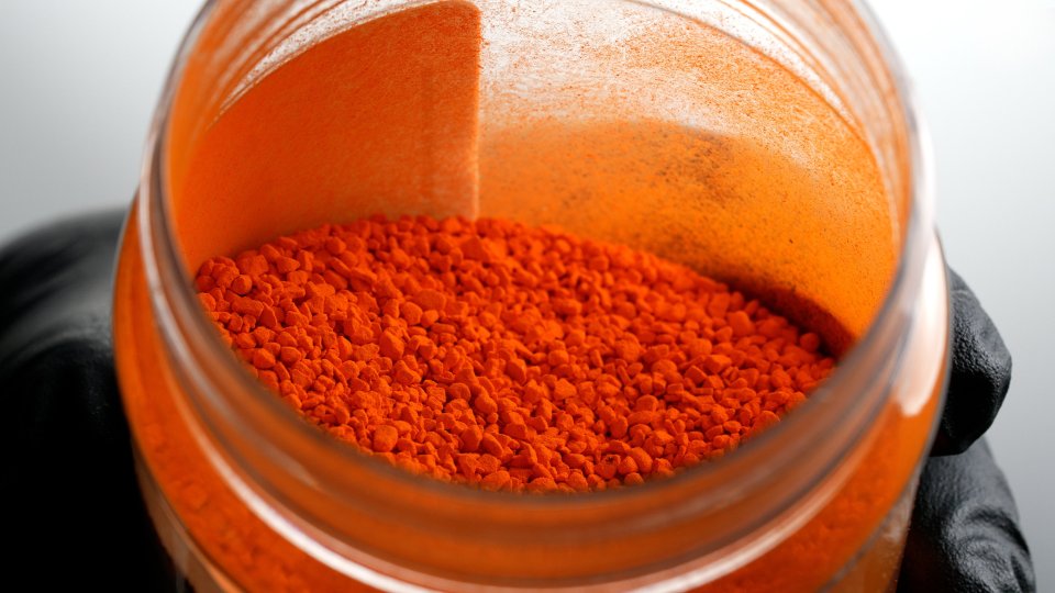 a jar of orange powder is being held in someone 's hand