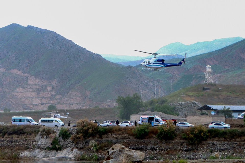 a helicopter is flying over a valley with mountains in the background