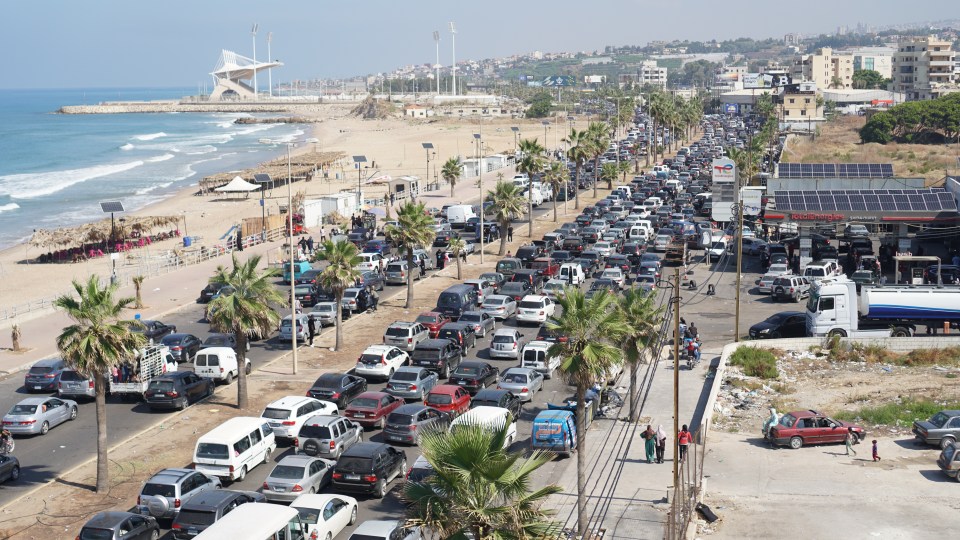 a busy street with a gas station in the background