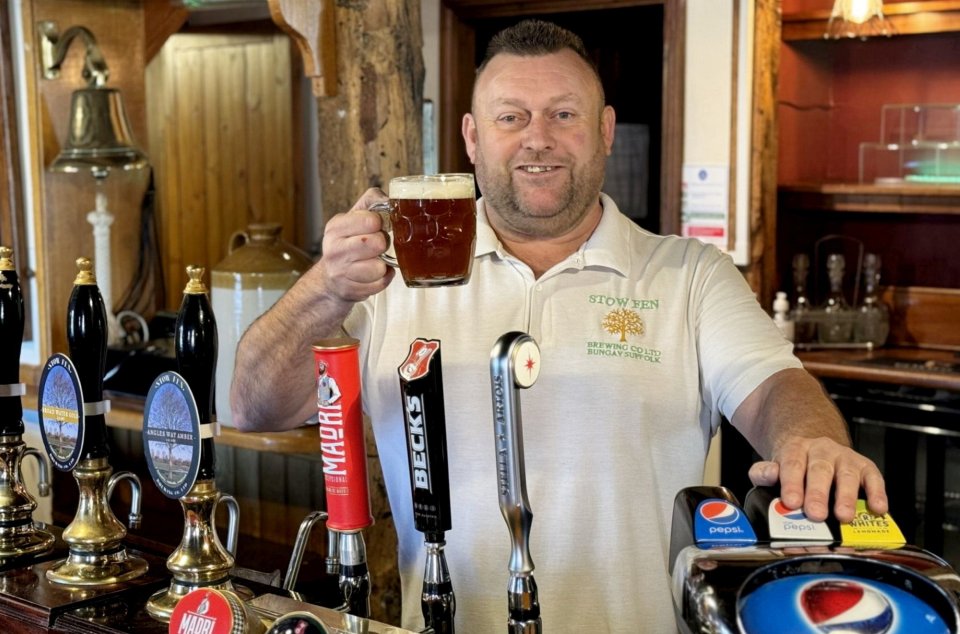 a man wearing a shirt that says stoween holding a mug of beer