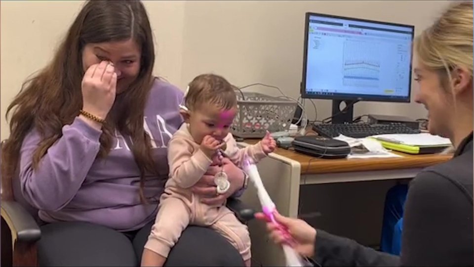 a woman in a purple gap sweatshirt holds a baby