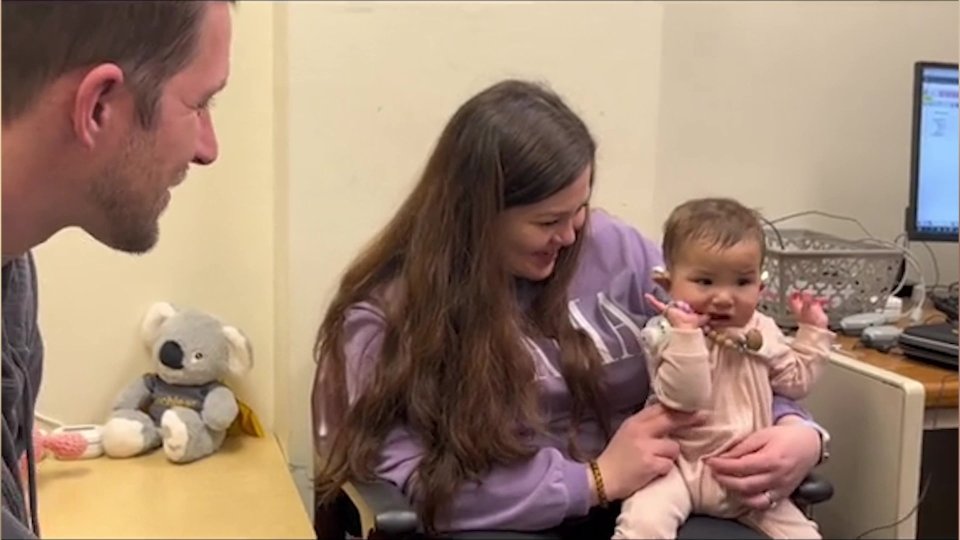 a woman in a gap sweatshirt is holding a baby