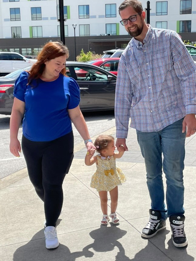 a man wearing converse shoes holds a baby 's hand