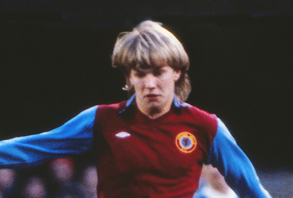 a soccer player wearing a maroon and blue jersey with a blue circle on the front