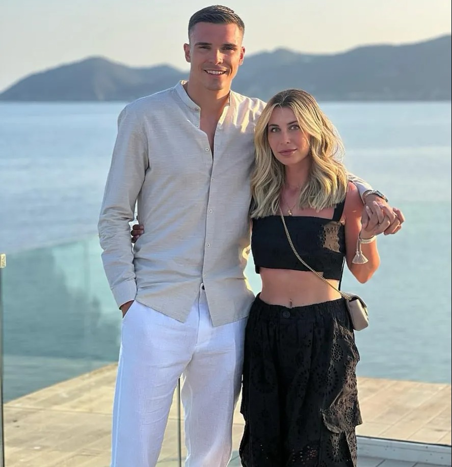 a man and a woman pose for a picture in front of the ocean