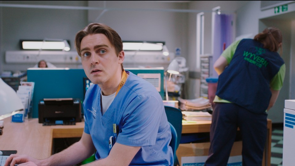 a man sitting at a desk with a wyvern vest on his back