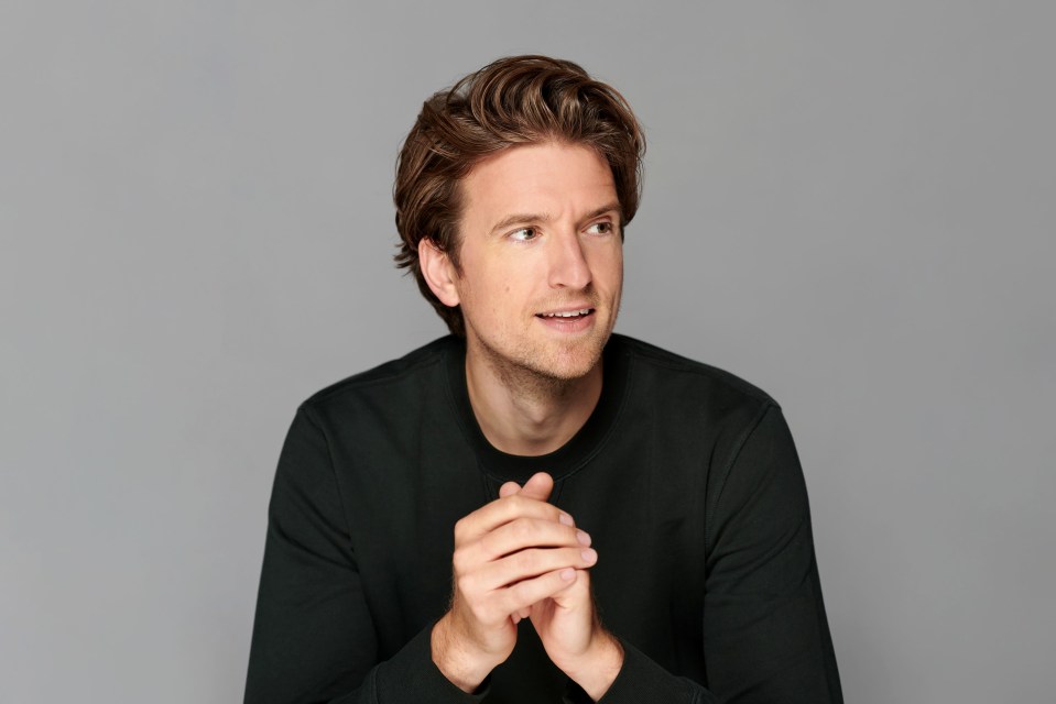 a man in a black sweater with his hands folded