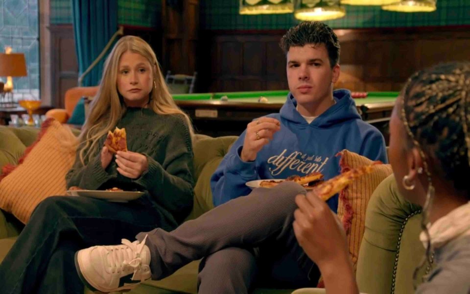 a man wearing a hoodie that says " i 'm not the different " is eating pizza