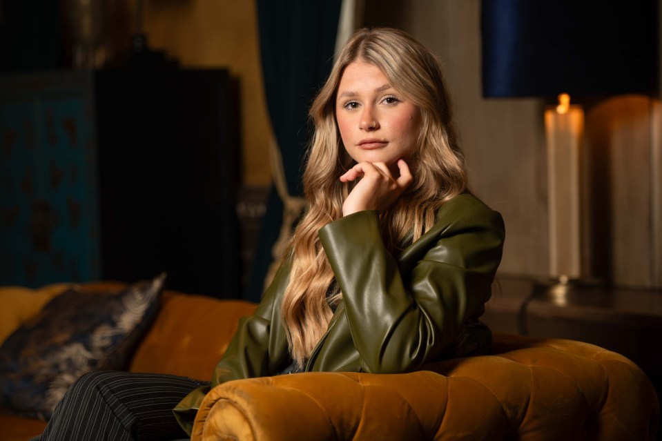 a woman in a green leather jacket sits on a yellow couch