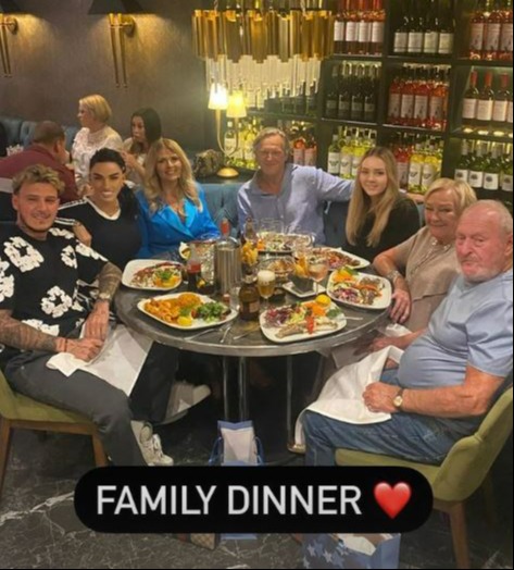 a group of people are sitting around a table with plates of food .