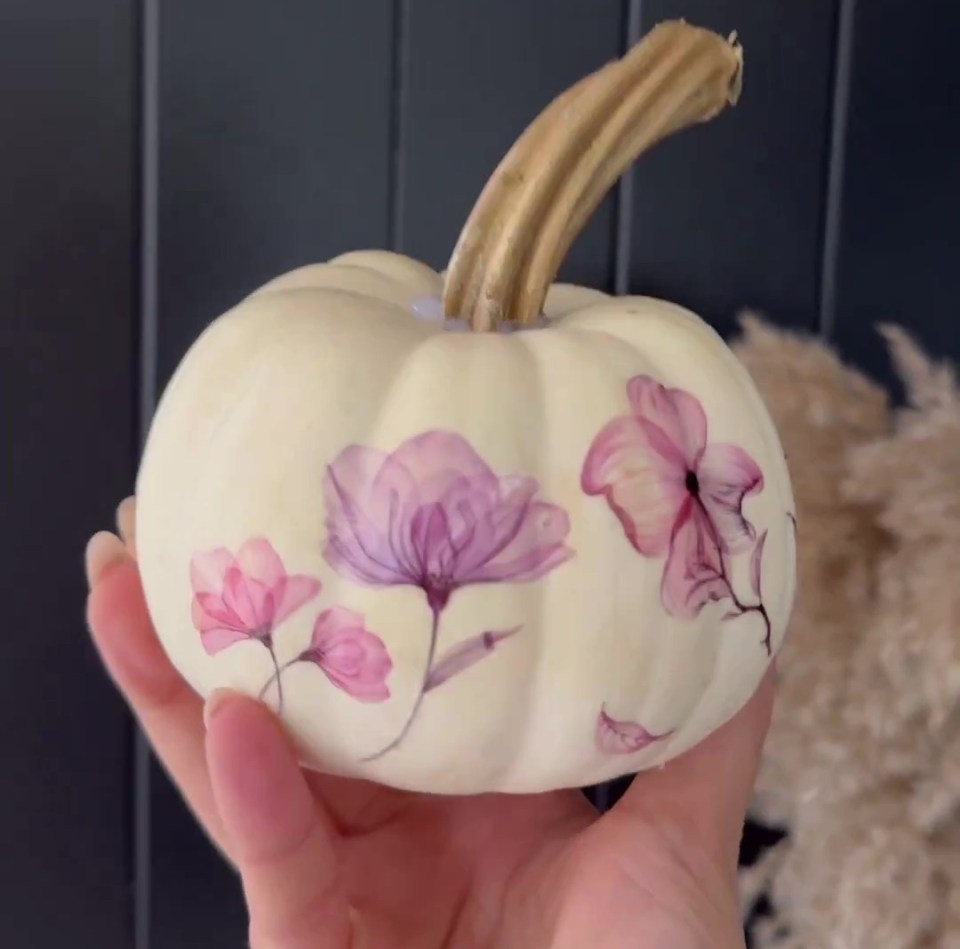 a white pumpkin with pink flowers painted on it