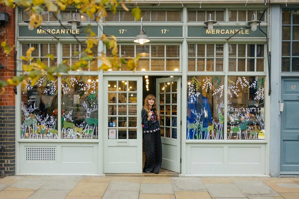 a woman stands in front of a store called mercantile