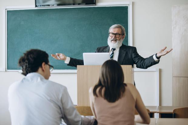 a man with a beard stands at a podium giving a lecture