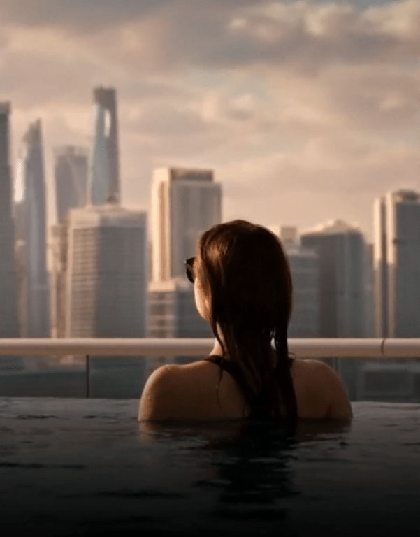 a woman is swimming in a pool with a city skyline in the background