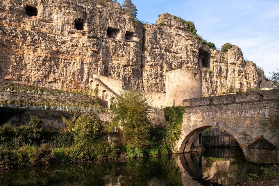 a bridge over a river with a cliff in the background