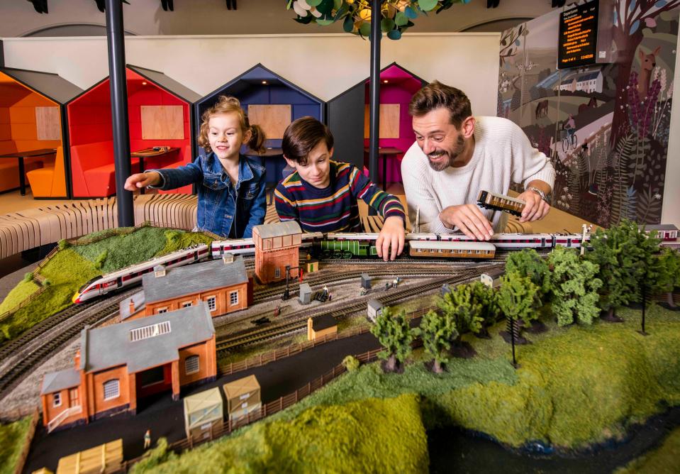 a man and two children are playing with a model train set