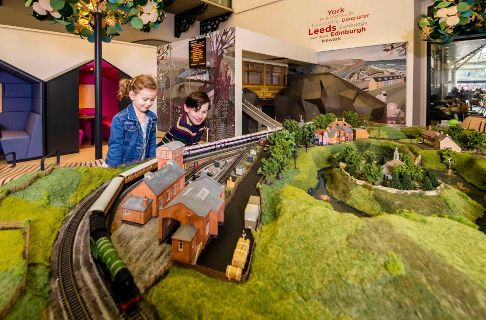 two children are looking at a model train set in york