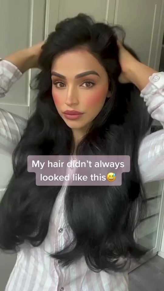 a woman with long black hair holds her hair in her hands