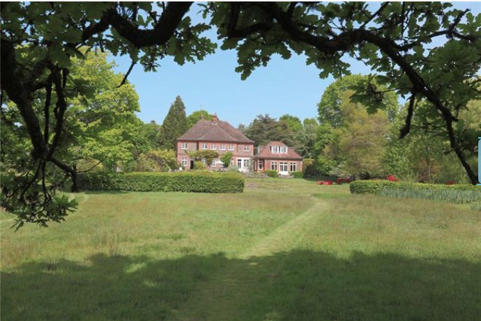 a large house sits in the middle of a lush green field