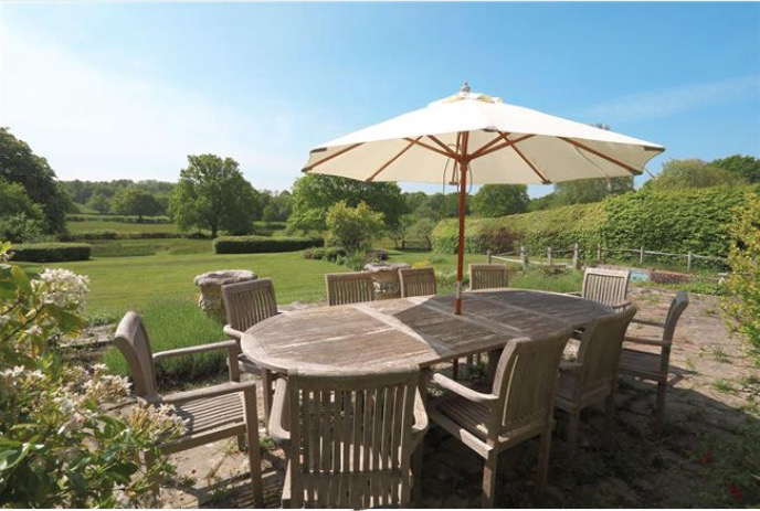 a table and chairs under an umbrella in a garden