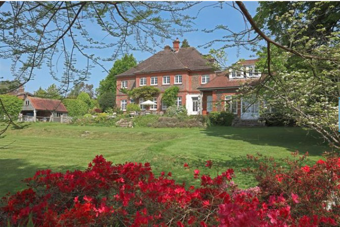 a large red brick house sits in the middle of a lush green field