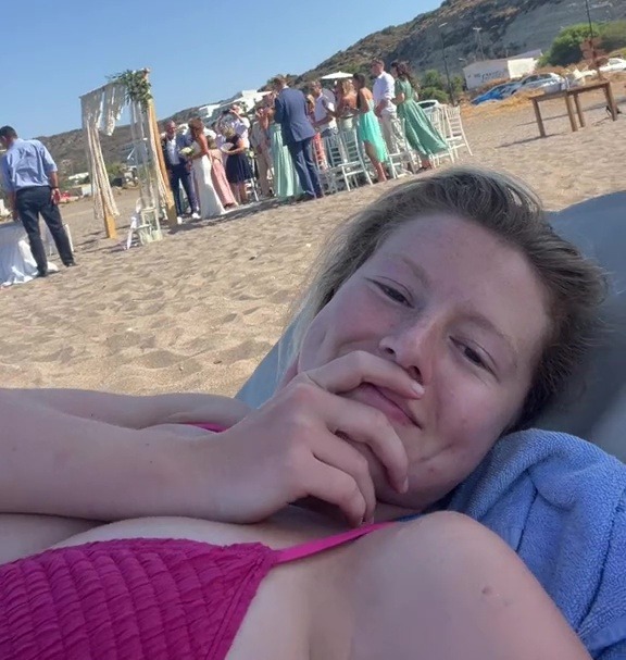 a woman in a pink bikini is laying on the beach