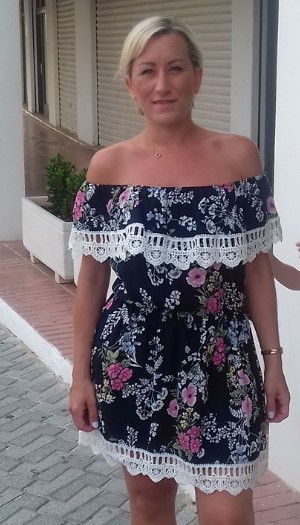 a woman is wearing a floral off the shoulder dress