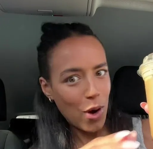 a woman is sitting in a car holding a cup of coffee .