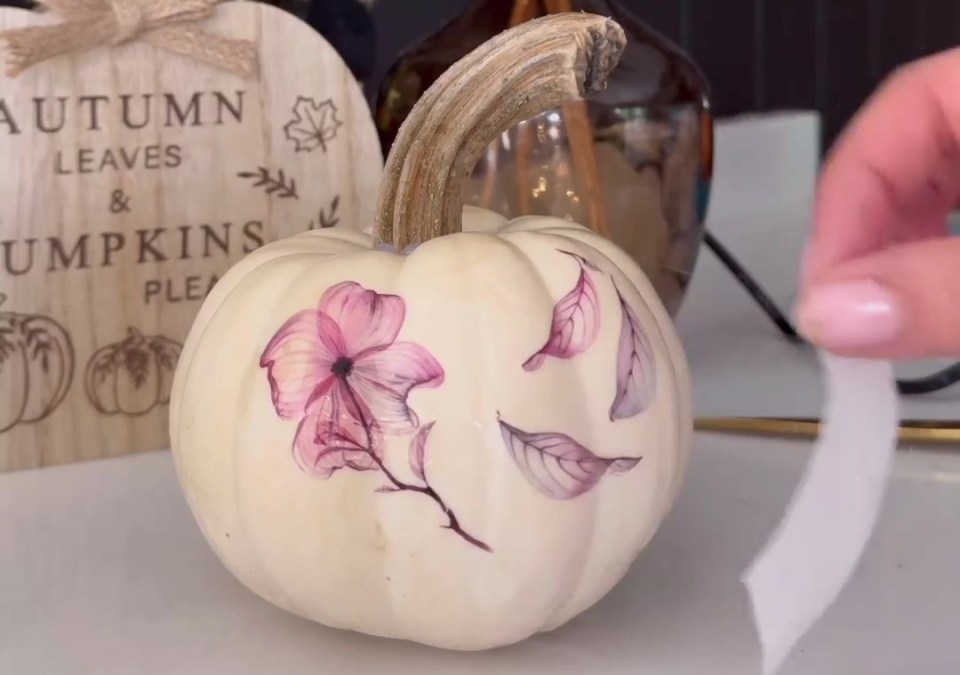 a white pumpkin with pink flowers painted on it