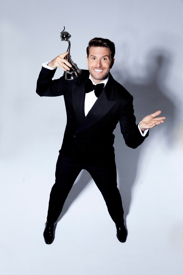 a man in a tuxedo is holding a trophy