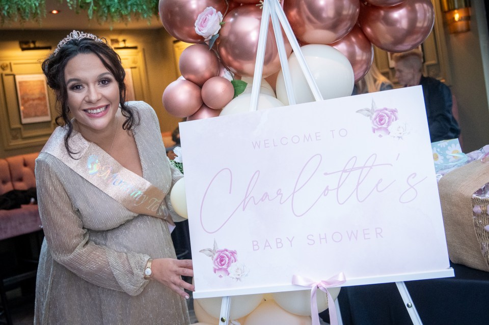 a pregnant woman holds a welcome to charlotte 's baby shower sign