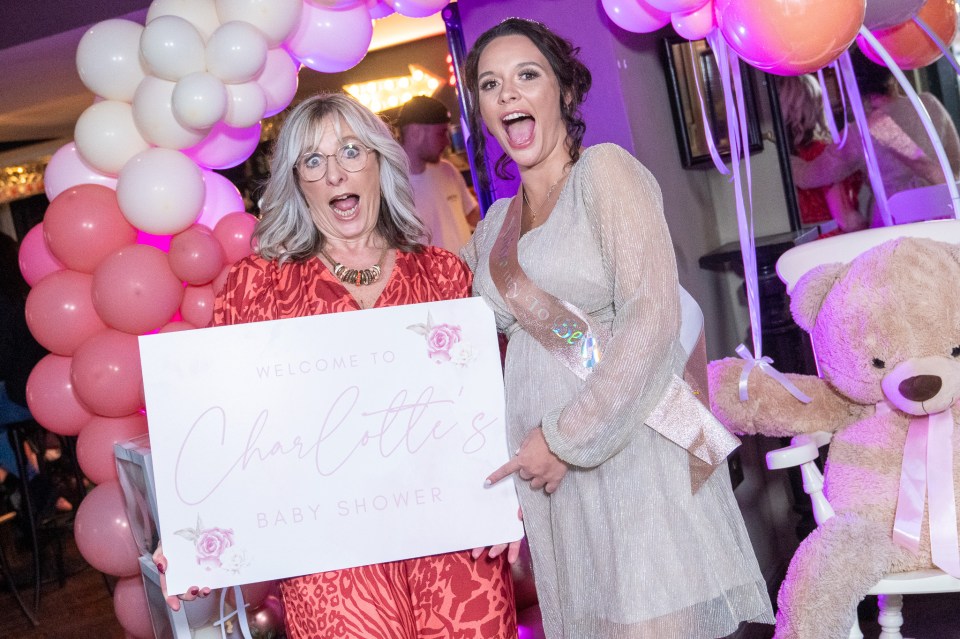 two women holding a welcome to charlotte 's baby shower sign