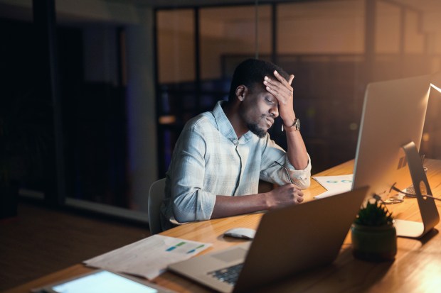 a man sitting at a desk with his hand on his head