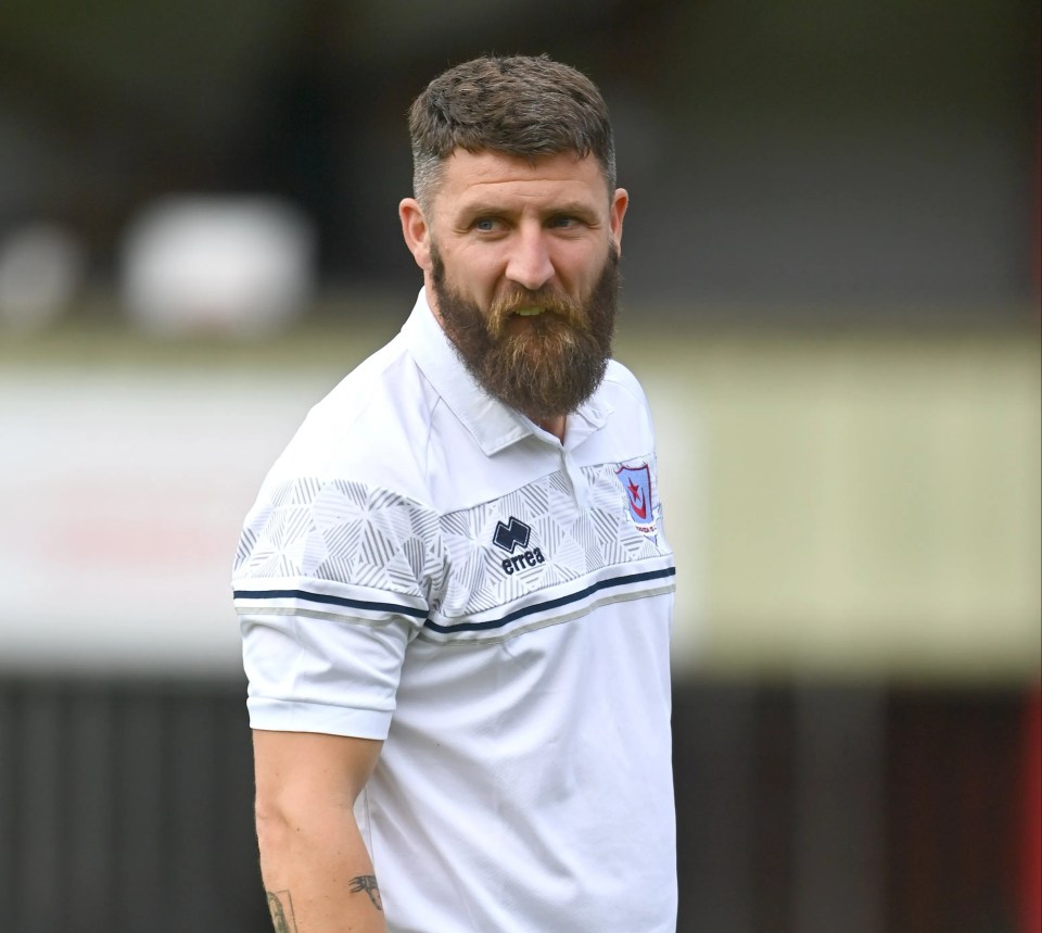 a man with a beard wears a white errea shirt