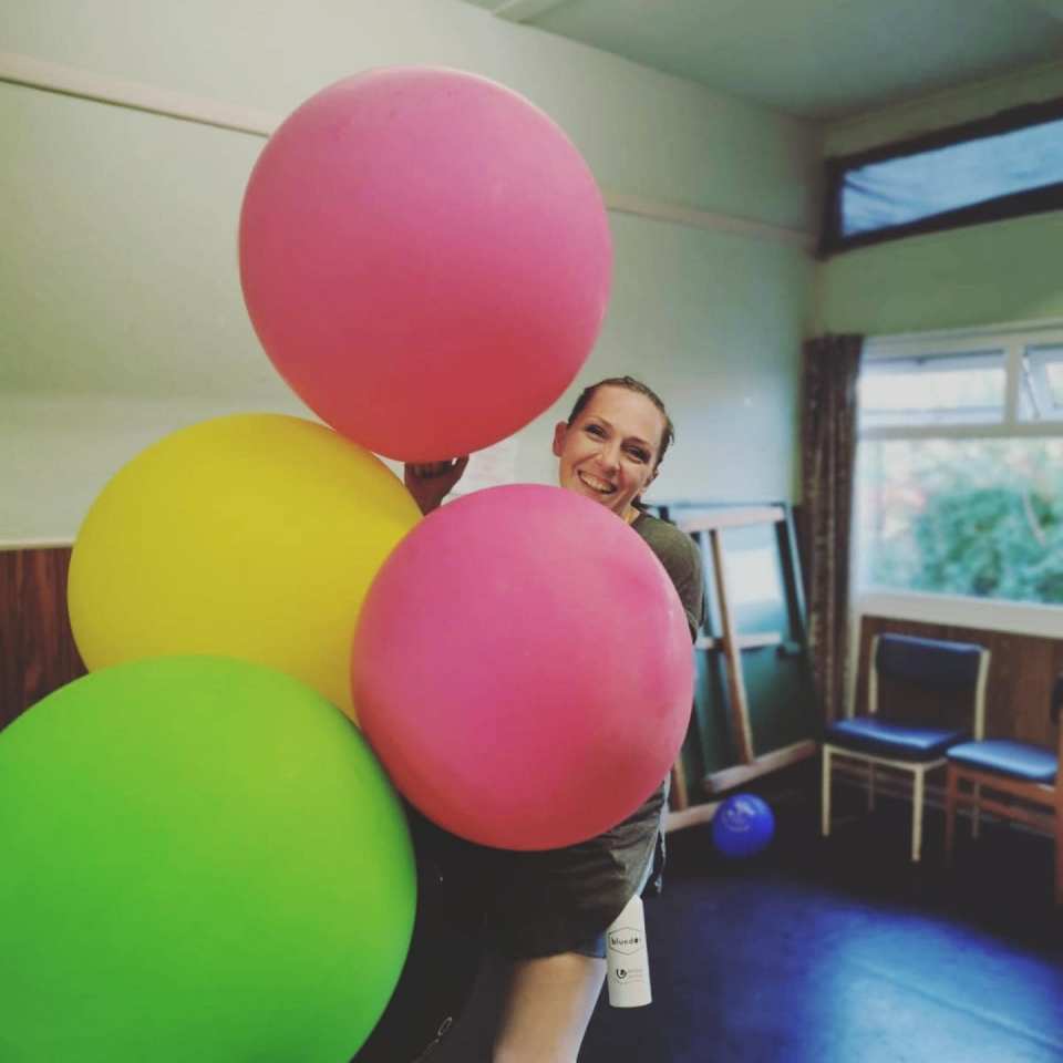 a woman is holding a bunch of colorful balloons and a bottle of shampoo