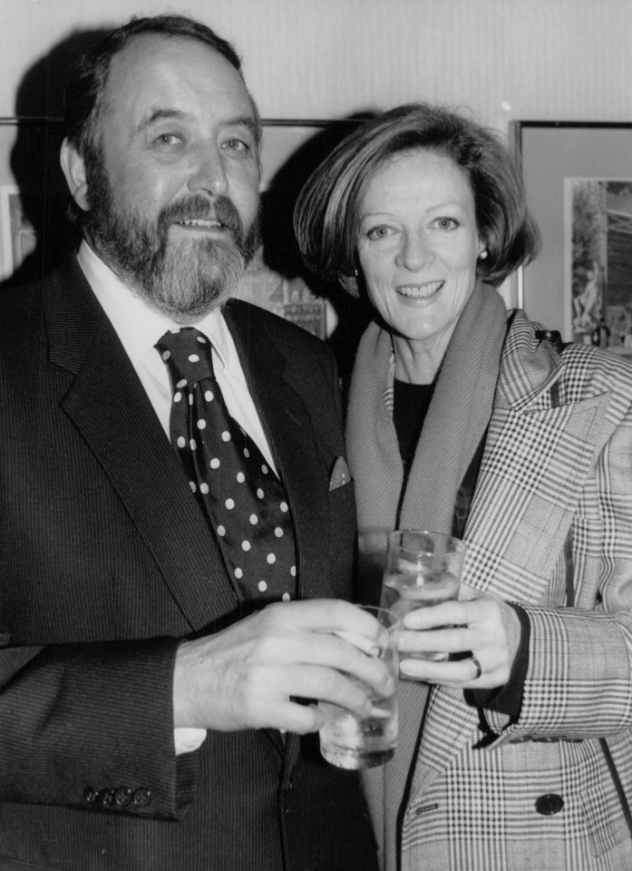 a man in a suit and tie stands next to a woman in a plaid jacket