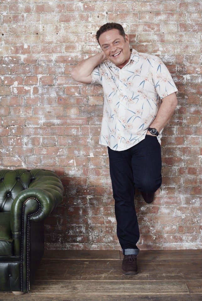 a man leans against a brick wall next to a green chair