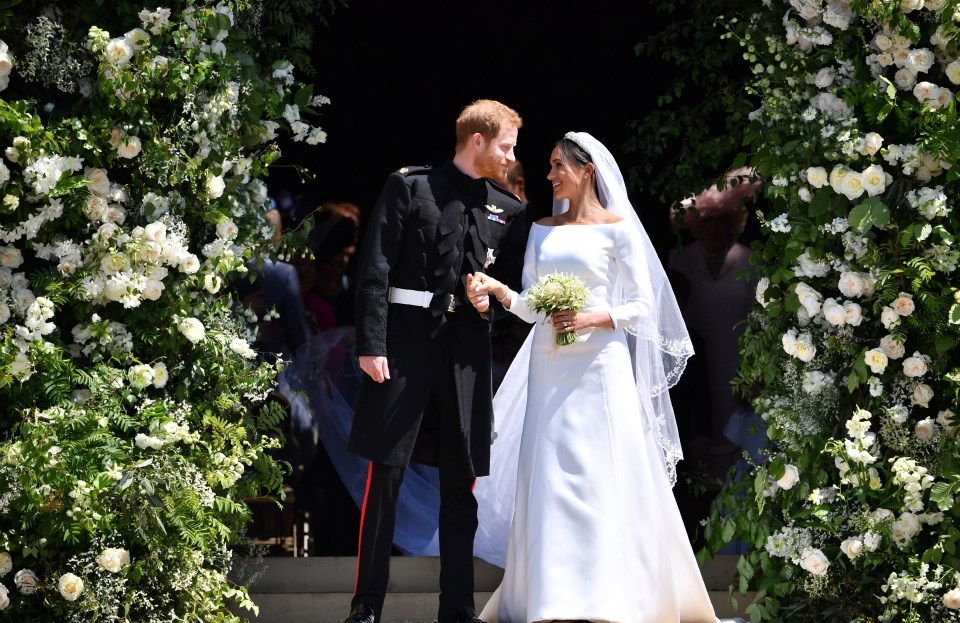 a bride and groom are standing in front of a floral archway