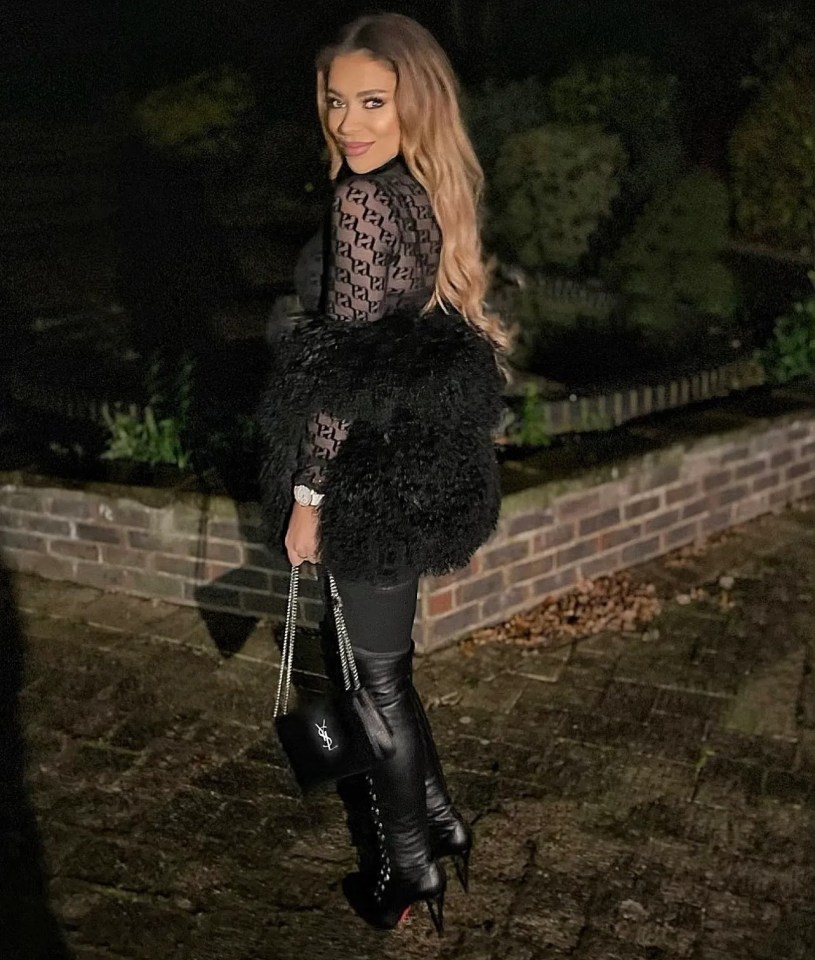 a woman wearing a black fur coat is standing in front of a brick wall