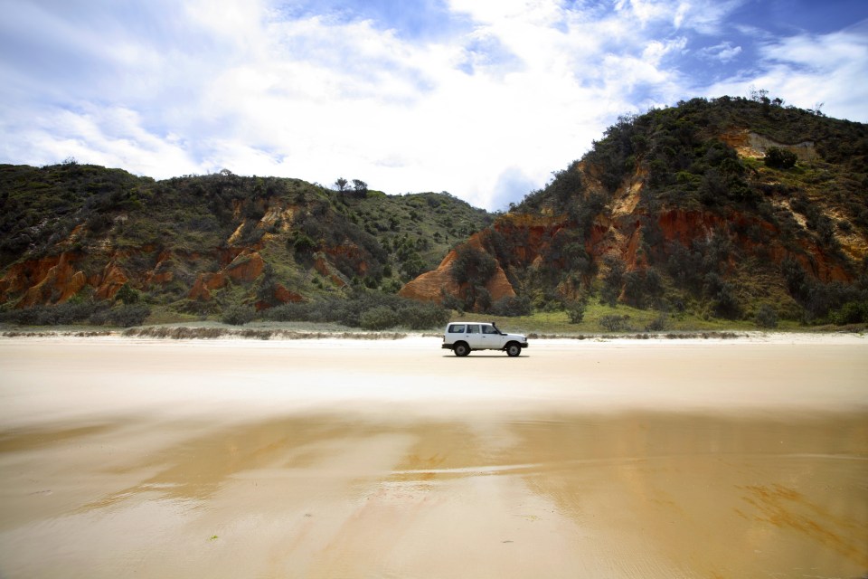 a white van is parked on a sandy beach