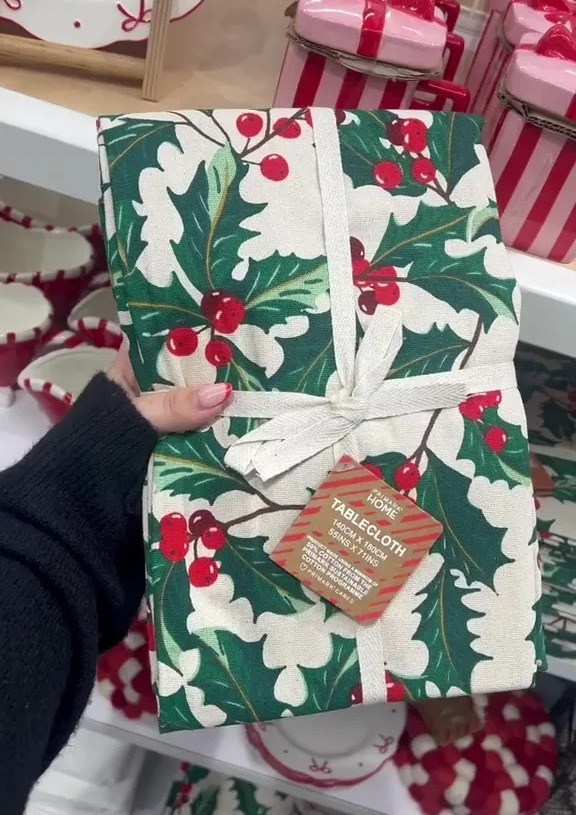 a person is holding a tablecloth with holly on it