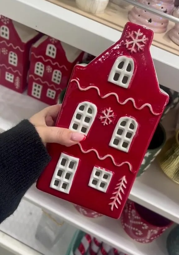 a person is holding a red house with white windows