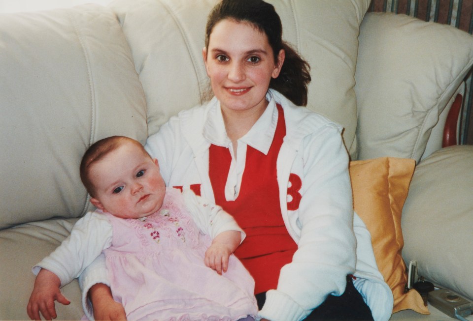 a woman holding a baby wearing a sweater with the letter b on it