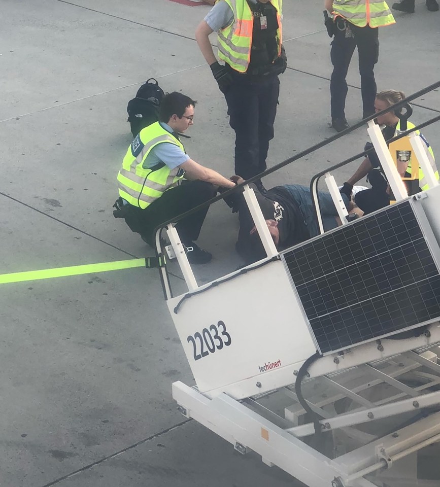 Cops restrain the drunk passenger in Munich after the flight was diverted