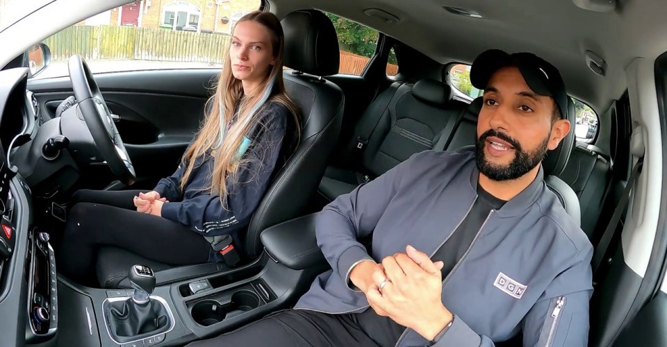 a man and a woman in a car with dgn driving written on the side