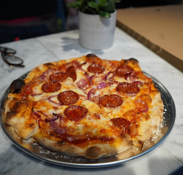 a pizza with pepperoni and onions on a metal pan